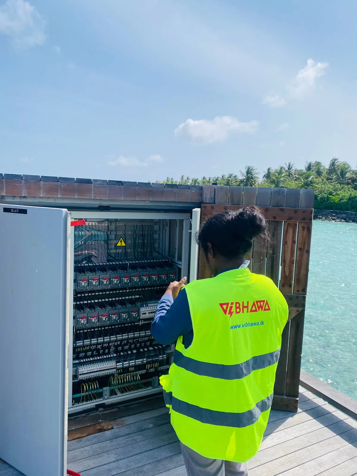 Vibhawa engineer inspecting an open distribution board on a resort jetty
