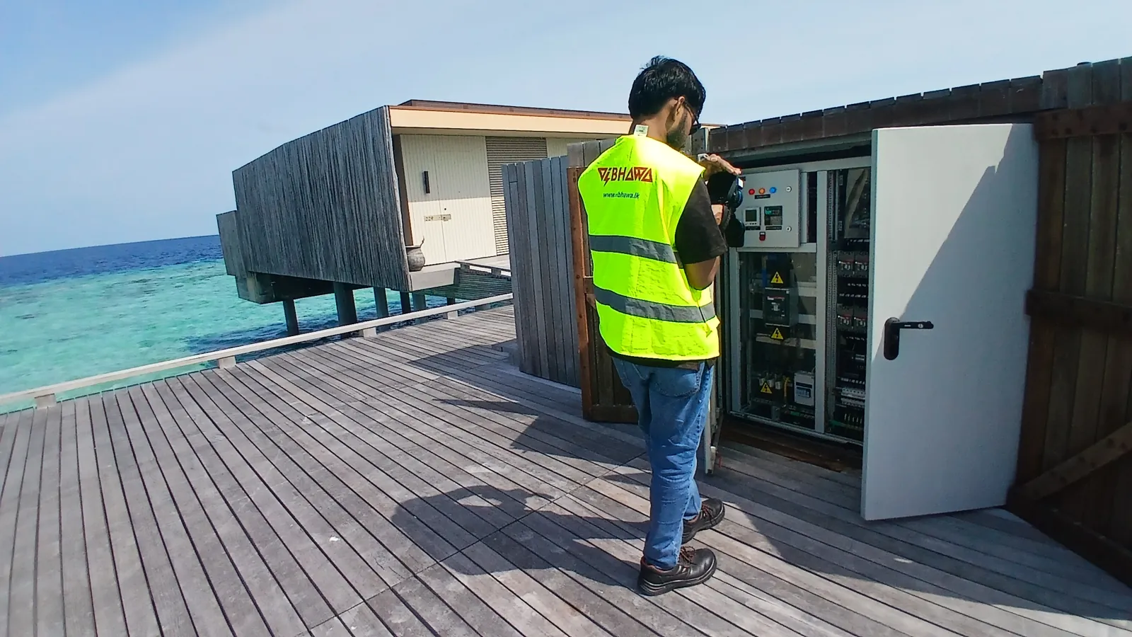 Vibhawa thermographer scanning a villa distribution board on an overwater walkway at Patina Maldives