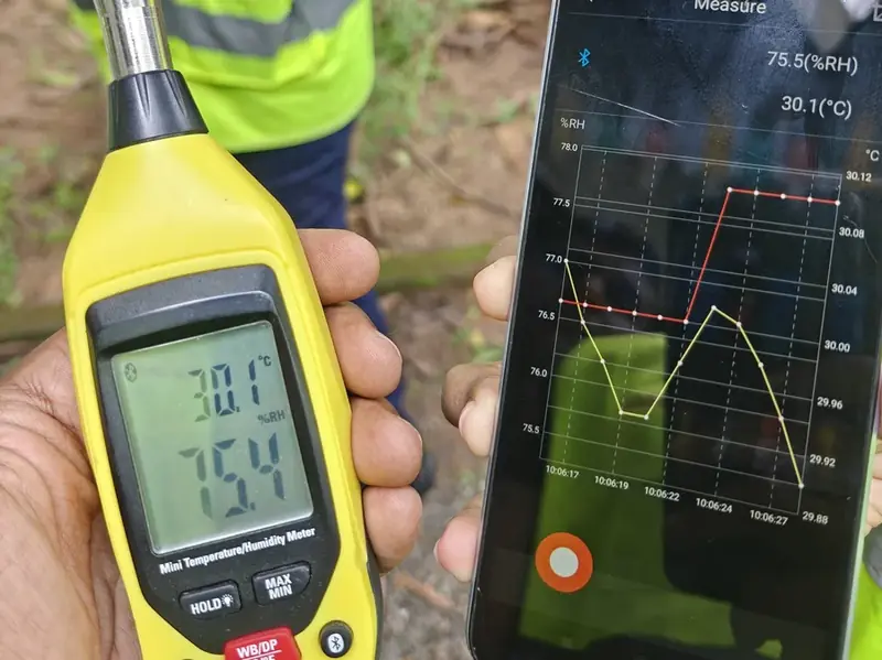 Handheld temperature and humidity meter streaming a live trend to a phone during an energy audit